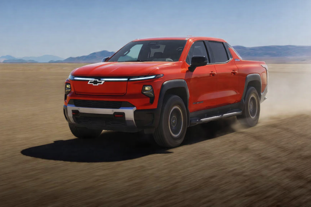 Red Chevrolet Silverado EV driving across a desert landscape kicking up dust.